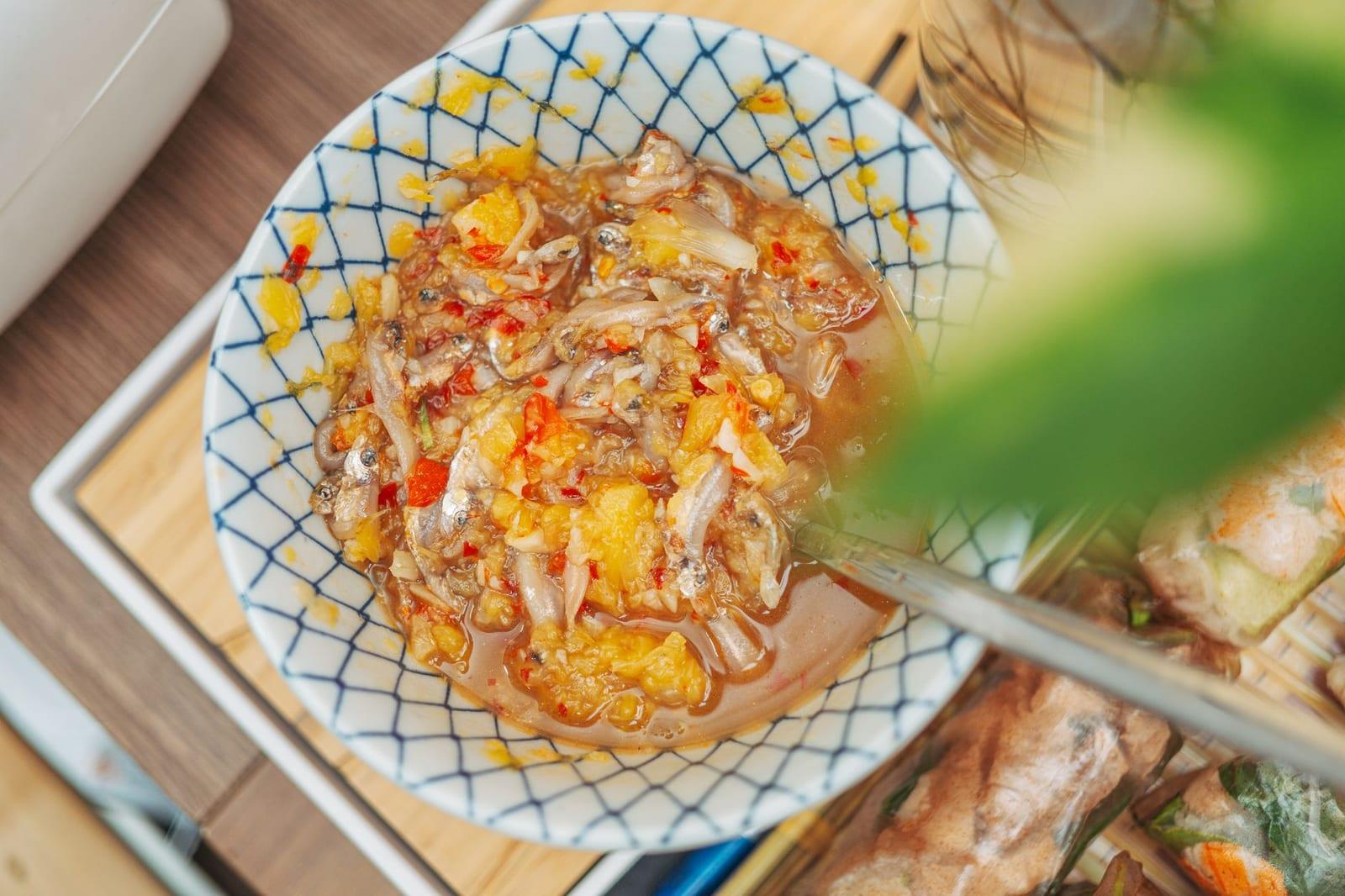 A small bowl of mắm nêm fermented-anchovy dipping sauce with chopped pineapple, garlic and red chilli