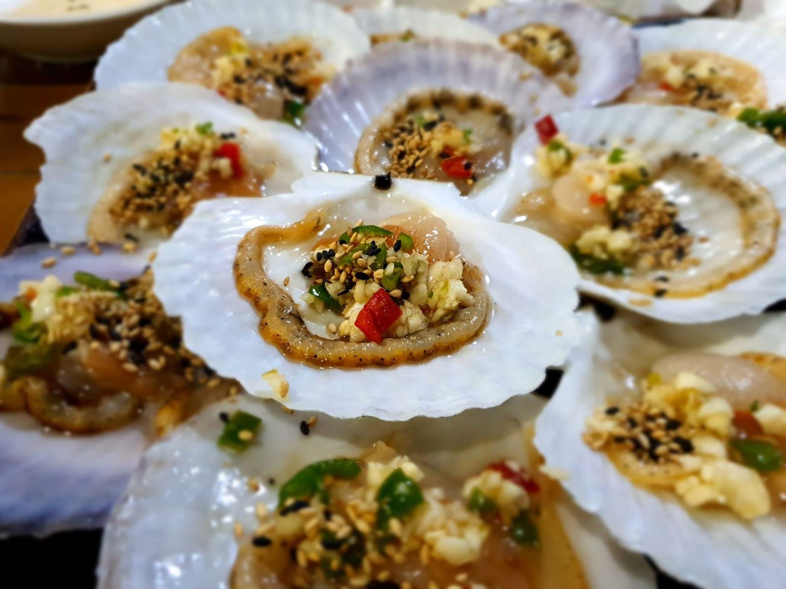 Grilled scallops topped with scallion oil and crushed peanuts on the half shell.